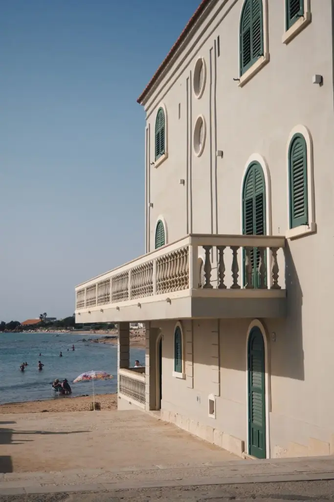 Charming building with balconies by a tranquil beach, ideal for travel imagery.